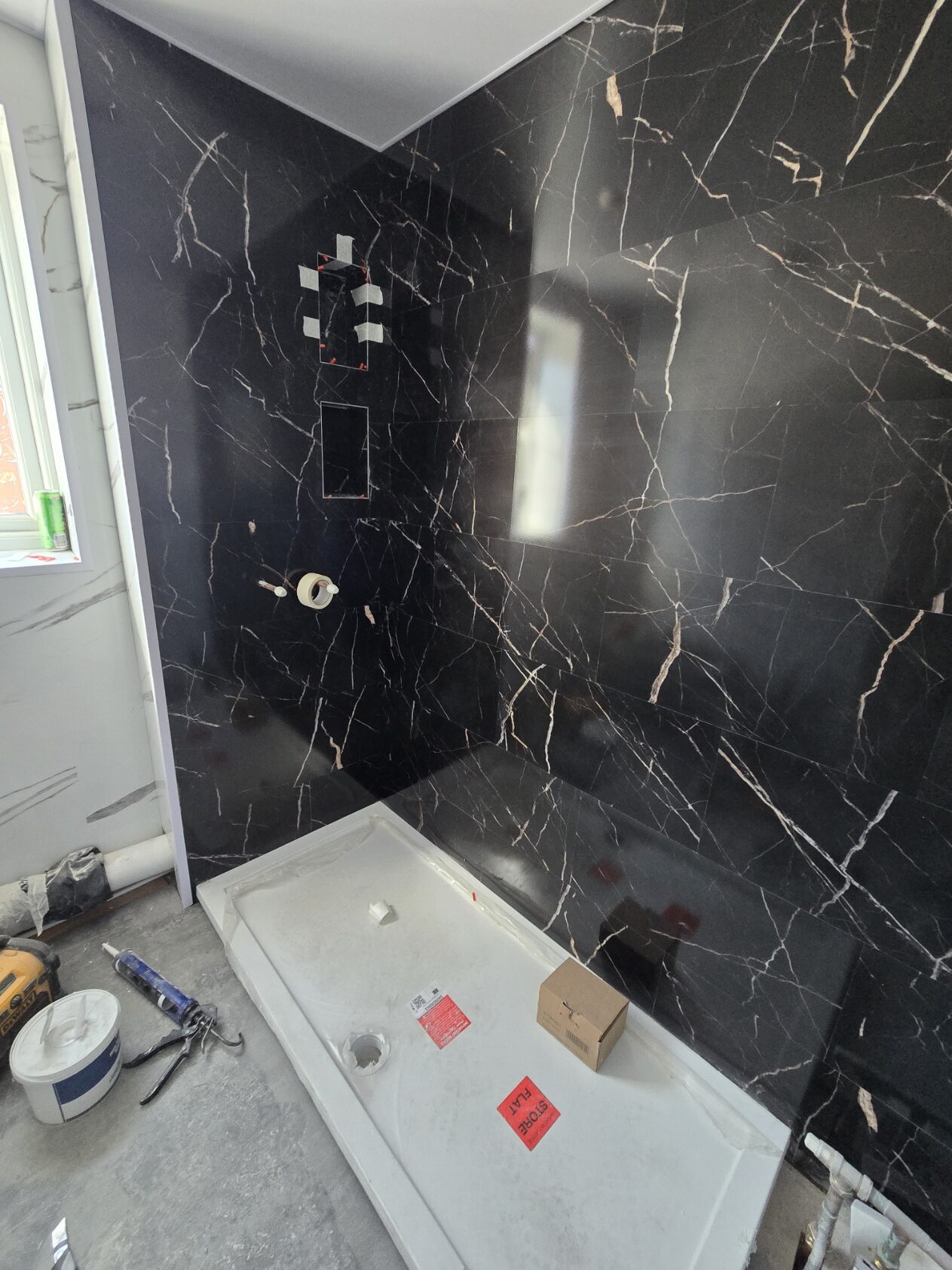 T40 SPC bathroom install in progress: black Calacatta marble walls going up, fittings ready